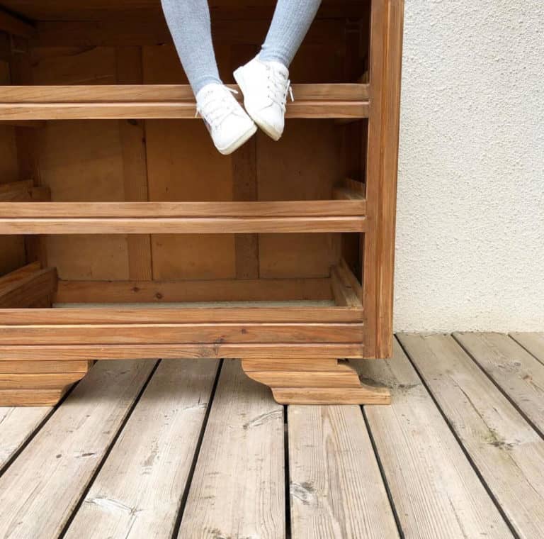 pieds de petite fille dans une commode art déco en bois en cours de restauration