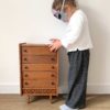 petite fille lisant un livre sur une commode en rotin pour poupée