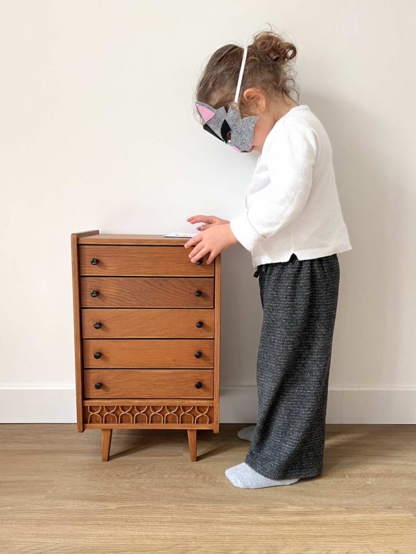 petite fille lisant un livre sur une commode en rotin pour poupée